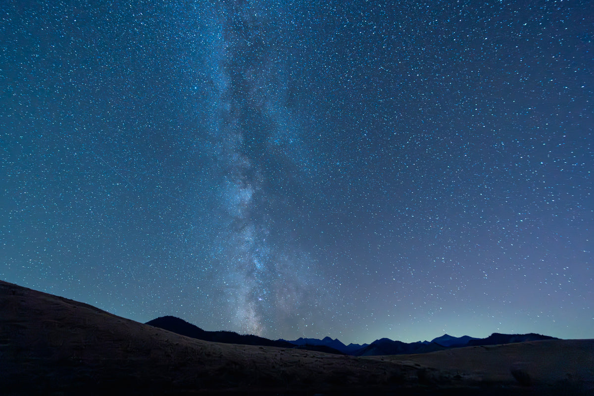 Deadhorse Lake Milkyway - Metal Print
Rectangular landscape image of the Milkyway galaxy over a silhouette of Hoodoo Peak in the Lake Chelan Sawtooth Wilderness; deep blue sky, bright white stars and a slight lavender haze over the mountains.  In the foreground, rolling hills are softly lit by starlight.