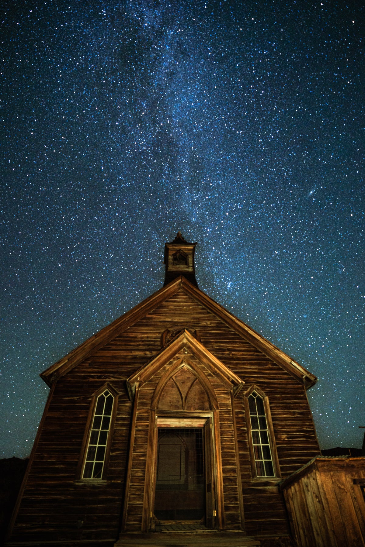 Bodie Church Light Painting - Metal Print 
Rectangular portrait image shows the brown façade of a ghost town church illuminated by flashlight beams. Bright white stars and the Milkyway appear in the dark blue sky above and around the bell tower.